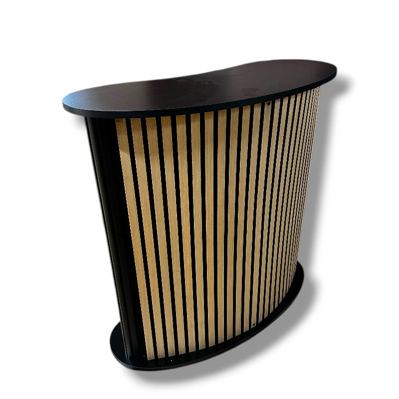 Bøygd diskur við hylldu. Forsíða við akustikplátu / trælamellum. B104 x D43 x H105 cm.